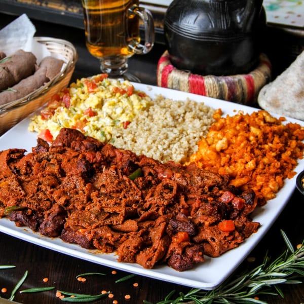 A large platter of Desta Ethiopian Kitchen's spicy red stew, scrambled eggs, and grains.