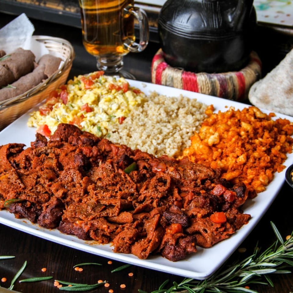 A large platter of Desta Ethiopian Kitchen's spicy red stew, scrambled eggs, and grains.