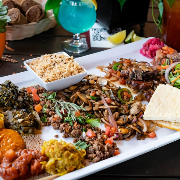 A large platter of Desta Ethiopian Kitchen's colorful dishes, including injera, rice, and various stews.