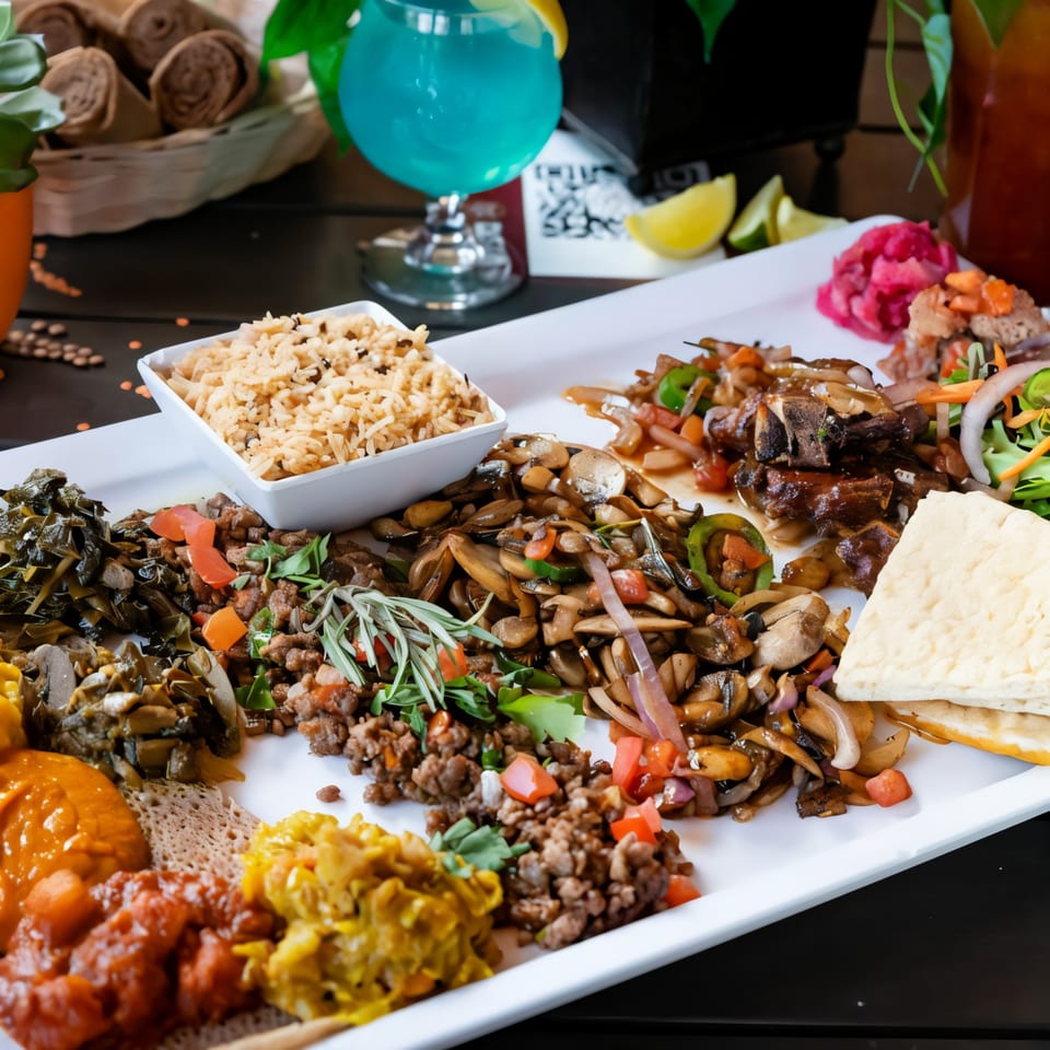 A large platter of Desta Ethiopian Kitchen's colorful dishes, including injera, rice, and various stews.
