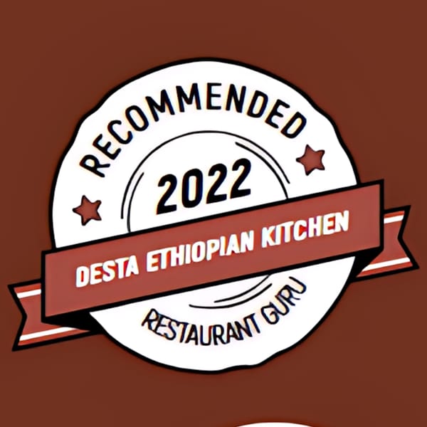 A white and red badge with "Recommended 2022 Desta Ethiopian Kitchen Restaurant Guru" text.