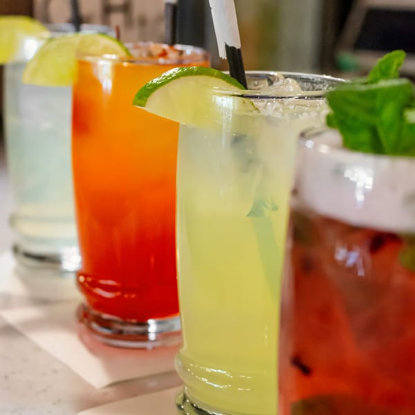 A row of colorful Desta Ethiopian Kitchen drinks, garnished with lime and mint.